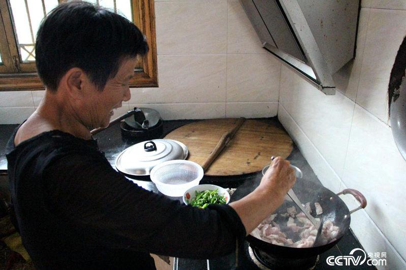 余秋明家里搞起农家乐,正在自家厨房给游客烧菜。